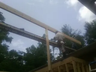 Carpenter setting a ridge beam over a new addition frame — Ice Dam Removal by Roofing Brothers in Bladenboro