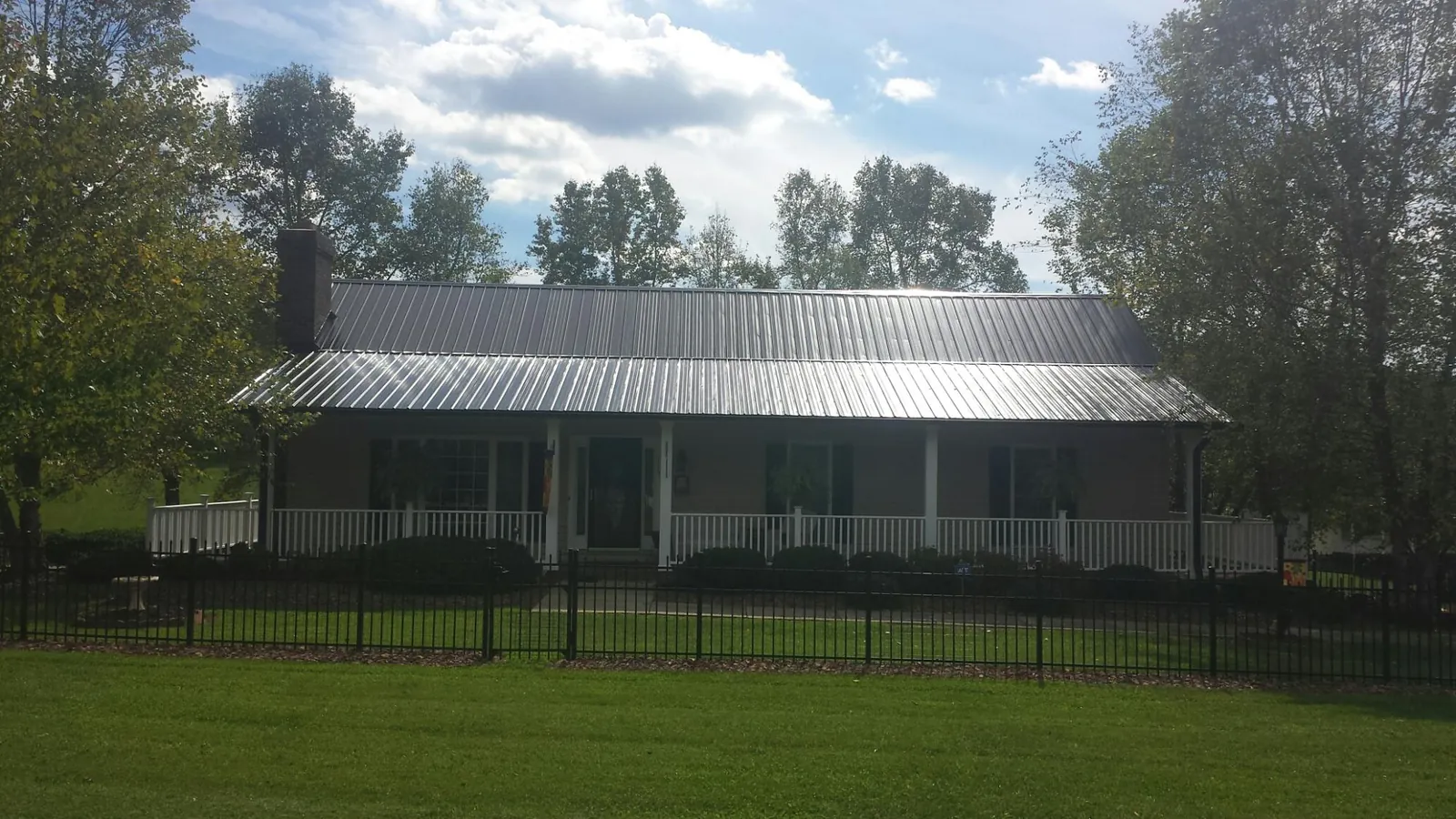 Gray metal roof on a brick ranch with a full width front porch — Gutter Guard Installation work by our crew in Bladenboro