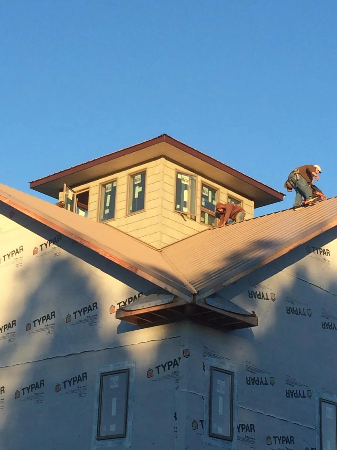 Roofers working around a rooftop cupola on a new metal roof at sunset — Roof Waterproofing in Bladenboro by Roofing Brothers